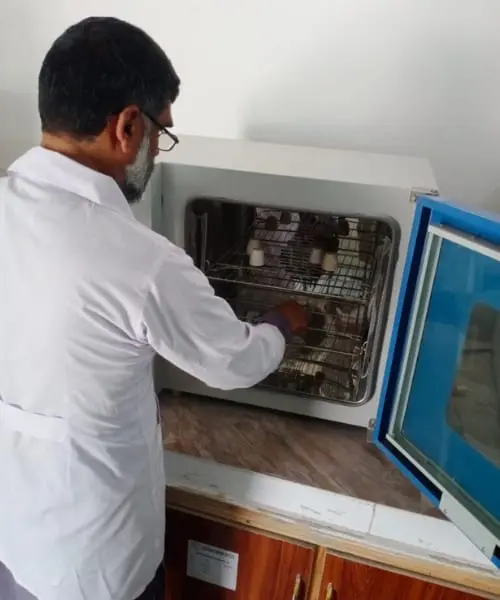A technician loading sample trays into a laboratory drying oven