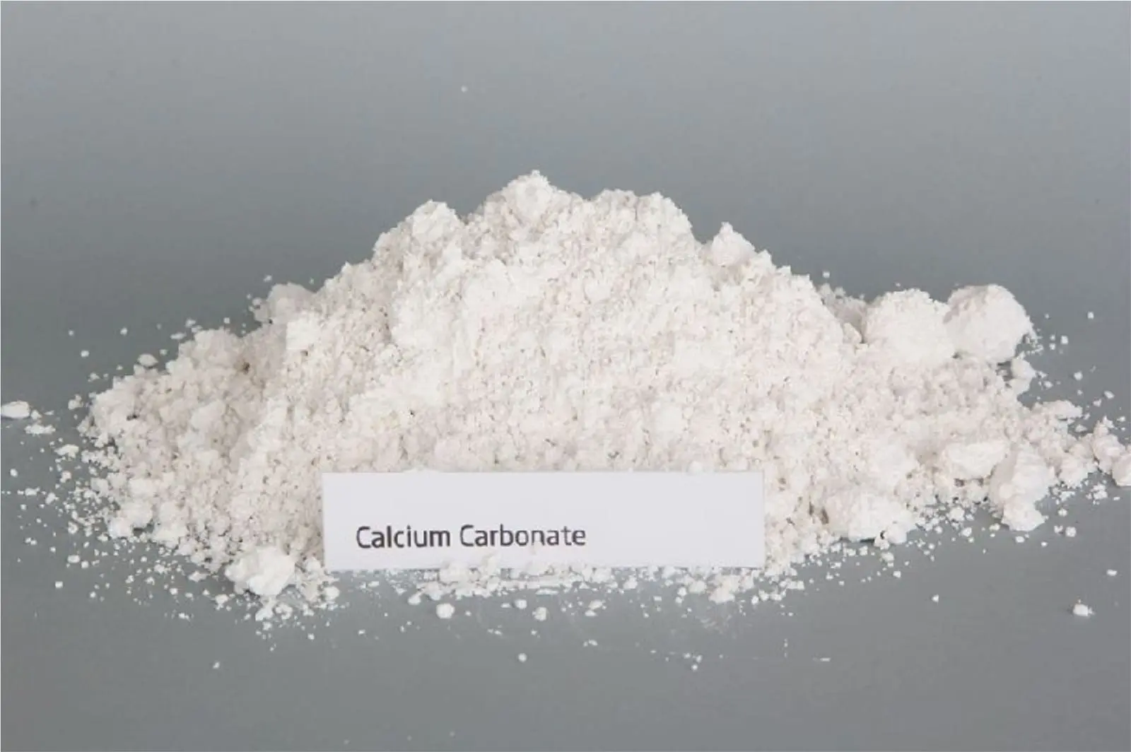 A pile of fine white powder with a small label reading Calcium Carbonate