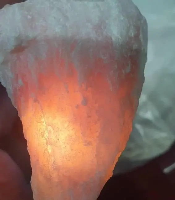 A rough salt lump held up to the light, glowing orange